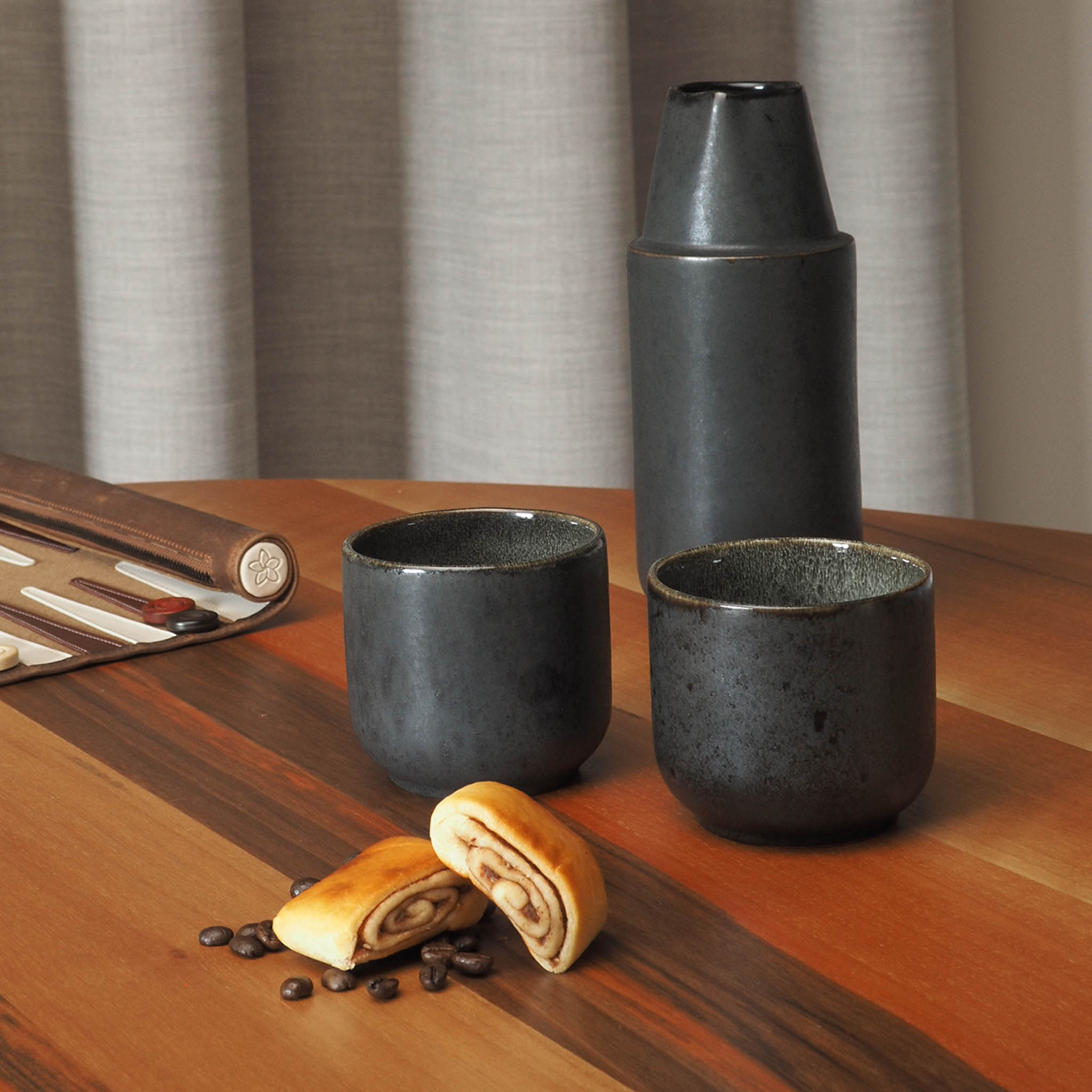 Karaffe schwarz mit Zimtschnecken und Kaffee auf Holztisch