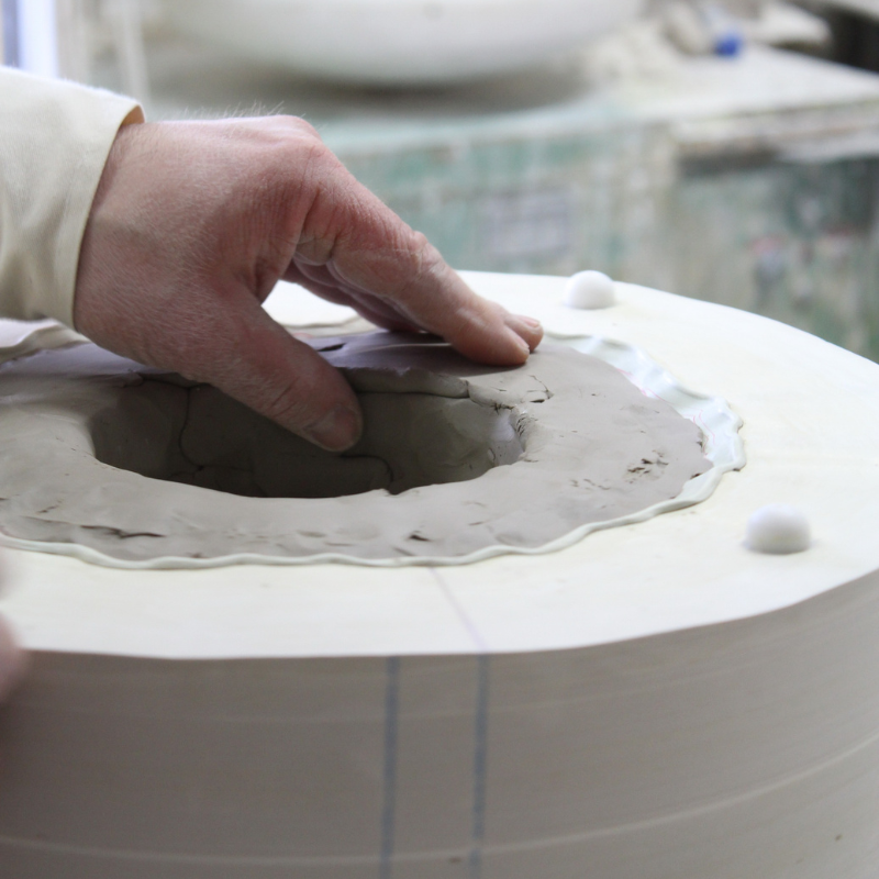 Handwerker formt grauen Ton in weißer Gipsform in Werkstatt — Salty Mind